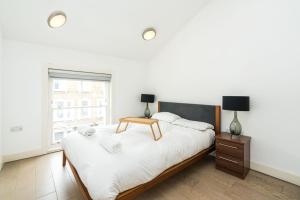 een witte slaapkamer met een groot bed en een raam bij Cozy 2 Bedroom / Earls Court / Balcony in Londen