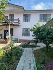 Uma casa branca com um caminho à frente. em Уютная вилла в центре Бишкека em Bishkek