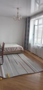 a bedroom with a bed and a rug on the floor at Уютная вилла в центре Бишкека in Bishkek