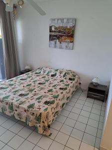 a bedroom with a bed with a floral comforter at Studio cosy les pieds dans l'eau à l'autre bord in Le Moule