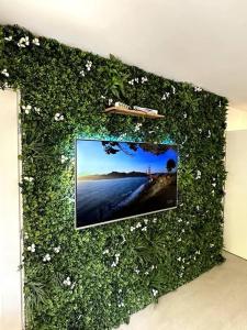 a wall covered in plants with a picture of a beach at Geneva Jungle Loft in Gaillard
