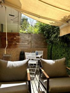 a patio with two chairs and a table and an umbrella at Geneva Jungle Loft in Gaillard