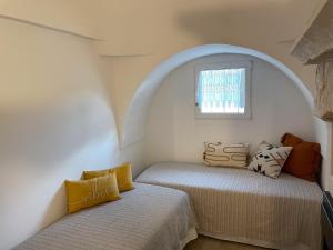 2 Betten in einem Zimmer mit Fenster in der Unterkunft Trullo vacanze di Cummà Rosa in Alberobello