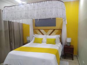 a bedroom with a bed with a yellow and white canopy at KAWETA COTTAGE in Yadinga