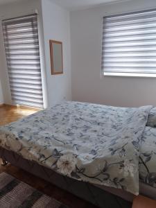 ein Bett in einem Schlafzimmer mit zwei Fenstern in der Unterkunft Apartman Sandi in Novi Travnik