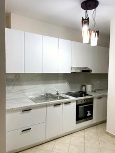 una cocina con armarios blancos y fregadero en New Bazaar Side Bliss 2 Bed Room apt with free garage en Tirana