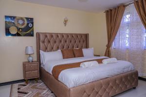 a bedroom with a large bed with white sheets at Milimani Apartment Comfy Homestay in Nakuru