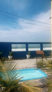 a swimming pool with a bench and the ocean at PÉ NA AREIA Apto Manfron in Itapoa