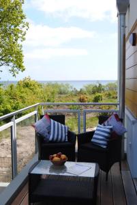 einen Balkon mit 2 Stühlen und einer Schale Obst auf einem Tisch in der Unterkunft Ferienwohnung Blaubärstrand in Juliusruh