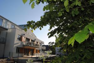 ein weißes Gebäude mit einem Balkon und einem Baum in der Unterkunft Ferienwohnung Blaubärstrand in Juliusruh