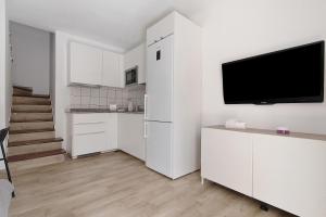 eine Küche mit weißen Schränken und einem Flachbild-TV in der Unterkunft Be Room Oasis Cozy Duplex in Maspalomas