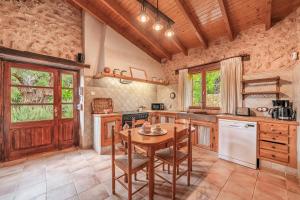 a kitchen with a wooden table and a wooden ceiling at Sa Sort in Alaró
