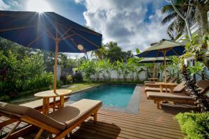 uma piscina com cadeiras e mesas e um guarda-sol em Titian Dewi Villa Ubud - 3 Bedroom Private Villa Close to Cretya Day Club em Tegalalang