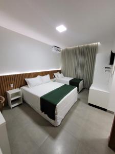 een hotelkamer met twee bedden en een televisie bij Pousada Chez bubônia in Novo Acordo