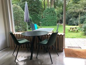uma mesa e cadeiras num quarto com uma janela em Veluwe Nature Home - 2-4 persons em Otterlo