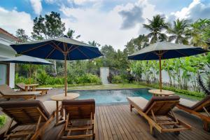 um pátio com cadeiras e guarda-sóis ao lado de uma piscina em Titian Dewi Villa Ubud - 3 Bedroom Private Villa Close to Cretya Day Club em Tegalalang