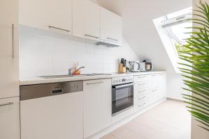 a white kitchen with white appliances and a plant at Airy Attic Apt.: Stylish Studio at Penzing Area in Vienna