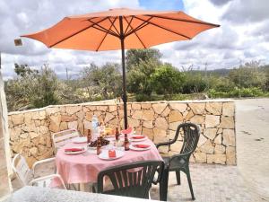 een tafel met een oranje parasol op een patio bij Casa Manuel J. J. M -Alfambras, Aljezur - Quiet Country House in Aljezur