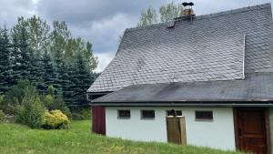 a white house with a black roof and some trees at Chalupa Lučany in Lučany nad Nisou