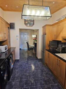 a kitchen with a black tile floor and wooden cabinets at Baron Park House in Clonmel