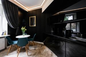 kuchnia z czarnymi ścianami oraz stołem i krzesłami w obiekcie Apartament Marylin w Krakowie