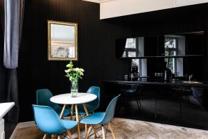 czarna kuchnia z białym stołem i niebieskimi krzesłami w obiekcie Apartament Marylin w Krakowie