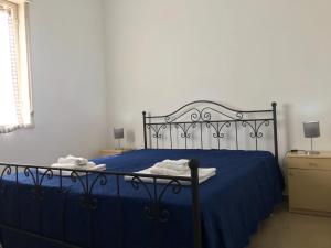 a bedroom with a blue bed with blue sheets and lamps at S.Giorgio Apartments in Sciacca