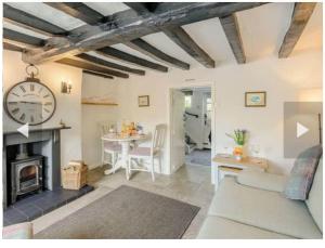 a living room with a fireplace and a clock on the wall at Stone Cottage, Idyllic Village in Ingham