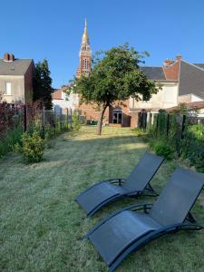 duas cadeiras num quintal com uma torre de relógio ao fundo em COTTAGE DU PARC em Albert