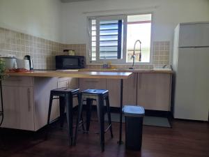 a kitchen with two bar stools and a counter with a sink at Fare Mihiau in Hauru