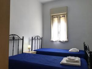 a bedroom with two blue beds and a window at S.Giorgio Apartments in Sciacca