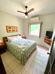 1 dormitorio con cama, ventana y TV en Pousada Banana Verde, en Ilhabela