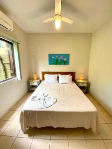 1 dormitorio con 1 cama blanca grande y 2 mesas en Pousada Banana Verde, en Ilhabela
