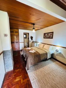 1 dormitorio con 1 cama grande y techo de madera en Chalé Rosa Flor, en Núcleo Mauá