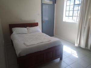 uma cama num quarto com uma janela em Trans-Africa equator hotel em Eldoret