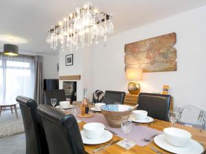 a dining room with a table with chairs and a chandelier at Pass the Keys Modern Coastal Home in Bull Bay in Amlwch