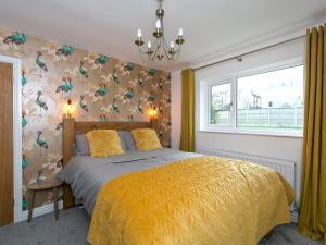 ein Schlafzimmer mit einem Bett mit gelber Tagesdecke und einem Fenster in der Unterkunft Pass the Keys Modern Coastal Home in Bull Bay in Amlwch