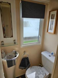 a bathroom with a sink and a toilet and a window at Rhuddlan Salty Smiles in Rhuddlan +13 photos