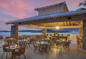 um restaurante na praia com mesas e cadeiras em The Westin Beach Resort & Spa at Frenchman's Reef em Frydendal