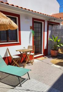 een patio met een tafel en stoelen en een huis bij Cantinho de Milfontes Jacuzzi in Vila Nova de Milfontes
