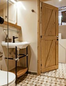 a bathroom with a sink and a wooden door at Pyrgi Cretan Living & Spa in Pírgos