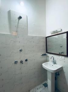 Baño blanco con lavabo y espejo en Bardia Eco Friendly Homestay, en Bhurkīā