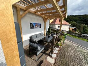 a patio with a table and chairs under a pergola at Ferienwohnung an der Thyrahöhe in Stolberg