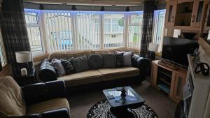 a living room with a couch and a tv at Rhuddlan Salty Smiles in Rhuddlan