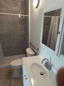 bagno con lavandino, servizi igienici e specchio di Islander Motel 