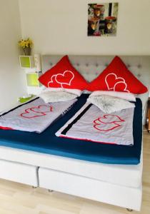 Una cama con almohadas rojas y blancas. en Eifelliebe Rott, en Roetgen