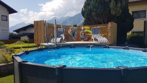 a pool with two children sitting in chairs next to a fence at s'KLINGI-Haus in Volders