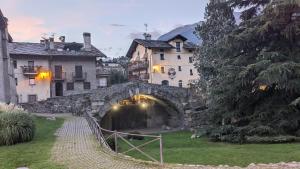 een stenen brug over een kanaal in een dorp bij Maison du Pont Romain in Aosta