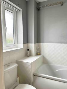 a white bathroom with a toilet and a window at The Gainsborough Mews-stylish & modern (sleeps 3) in Lincolnshire