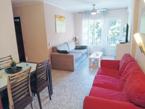 a living room with a red couch and a table at Habitaciones en Apartamento compartido DELICIAS ROOM Cerca del Mar, Aeropuerto, Ave y Metro in Málaga